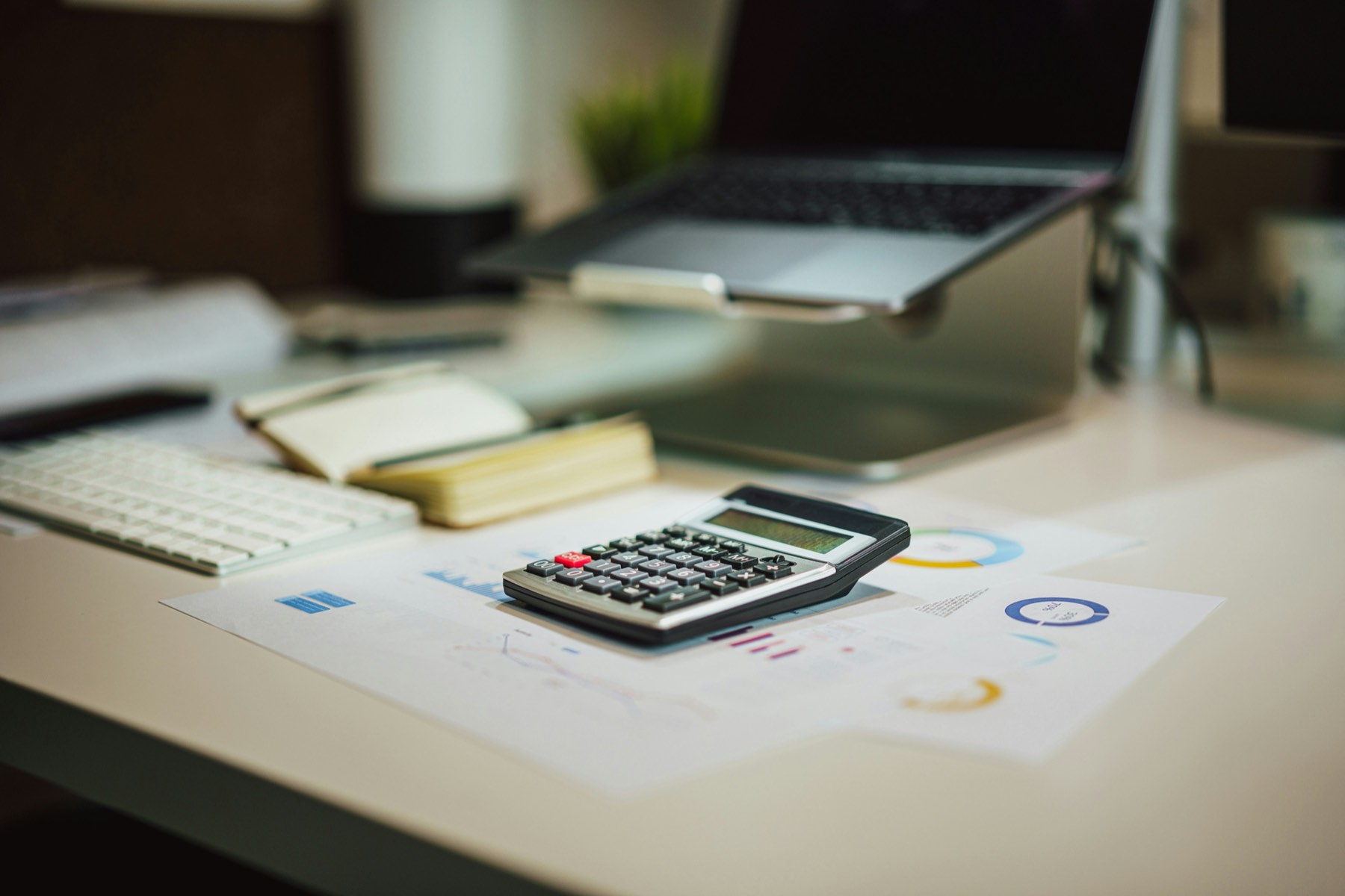 Calculator and financial charts on a desk representing the tax cost comparison between company types in Turkey