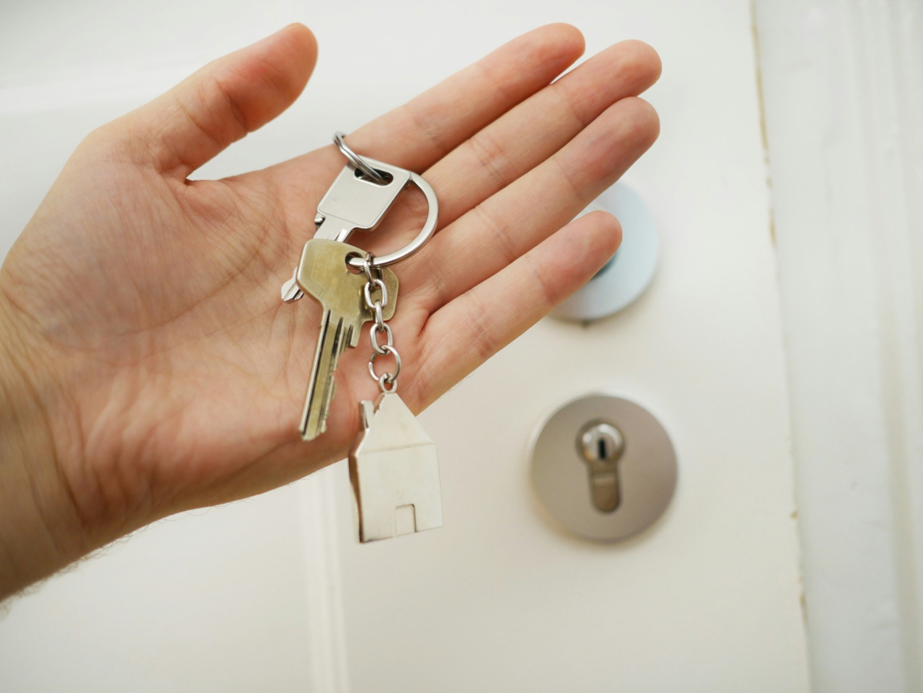 Hand holding house keys, representing property being contributed as capital to a company in Turkey